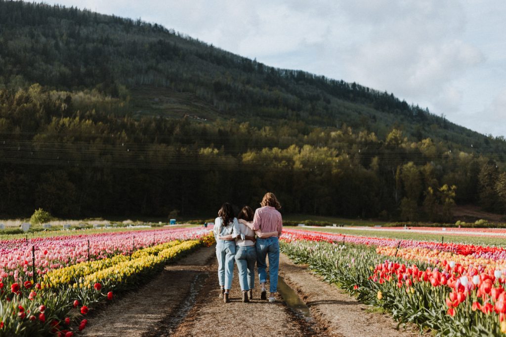 Three friends walking through a garden.