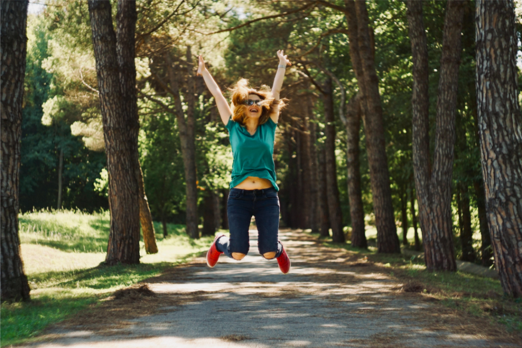 Woman jumping in air and smiling about the importance of senior mature friendship