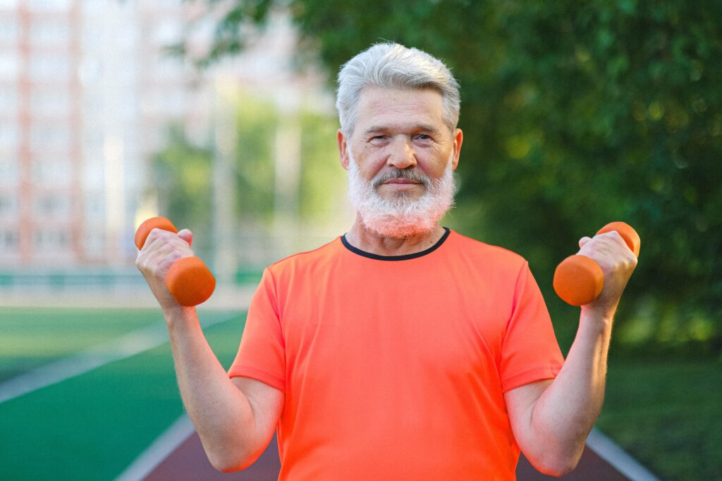 Older man smiling while exercising with dumbbells