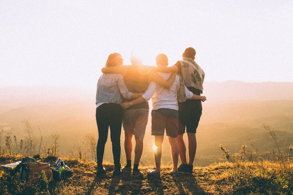 Friends arm-in-arm silhouetted by the sun.